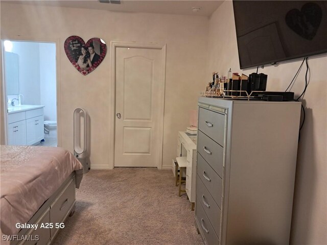 bedroom with light colored carpet, sink, and ensuite bath