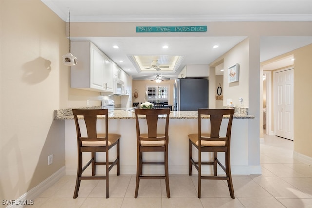 902 SW 48th Ter Unit 104, Cape Coral, FL 33914 - kitchen featuring white appliances, a peninsula, light stone countertops, a raised ceiling, and white cabinets