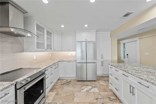 kitchen featuring backsplash, white cabinets, appliances with stainless steel finishes, and wall chimney range hood