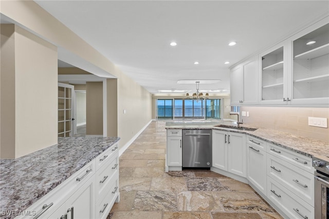 kitchen with tasteful backsplash, dishwasher, sink, white cabinets, and light stone counters