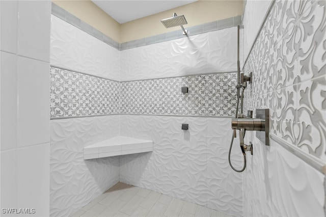 bathroom featuring tiled shower and tile walls