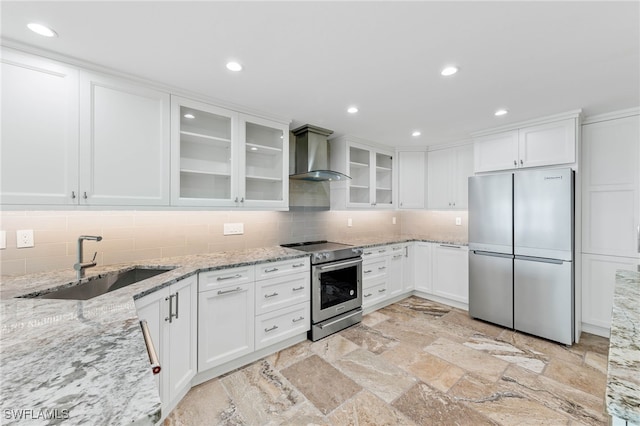 kitchen with white cabinetry, appliances with stainless steel finishes, sink, and wall chimney range hood