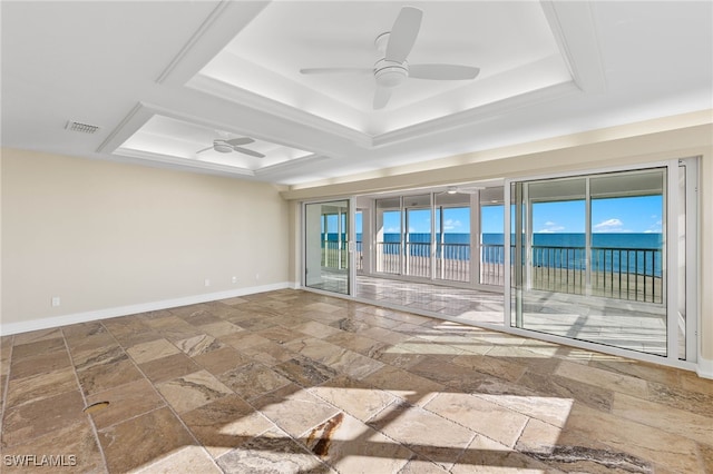 spare room with a tray ceiling, ceiling fan, and a water view