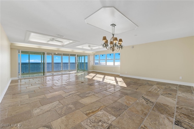 empty room with a water view, an inviting chandelier, and a tray ceiling