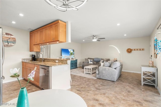 kitchen featuring sink, dishwasher, ceiling fan, light stone counters, and kitchen peninsula