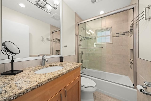 full bathroom with vanity, wood-type flooring, enclosed tub / shower combo, and toilet