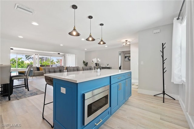 kitchen with stainless steel microwave, pendant lighting, a kitchen breakfast bar, a center island, and blue cabinetry