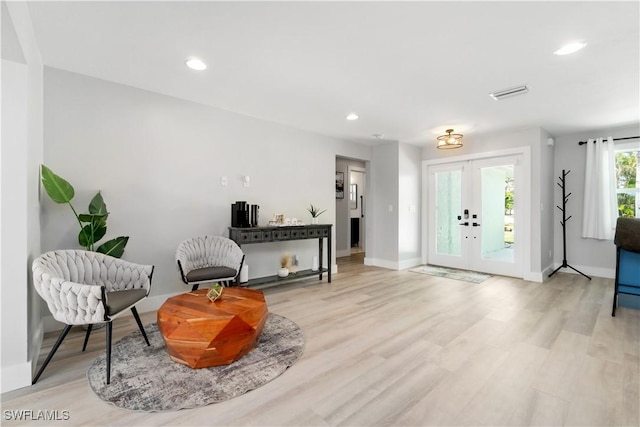 living area with french doors and light hardwood / wood-style flooring