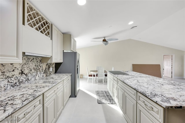 kitchen with lofted ceiling, tasteful backsplash, ceiling fan, light stone counters, and light tile patterned floors