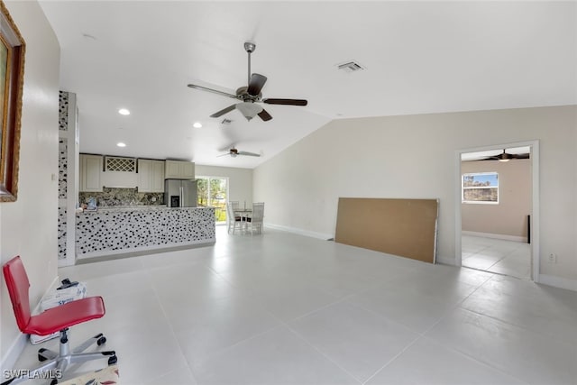 tiled living room featuring vaulted ceiling, ceiling fan, and plenty of natural light