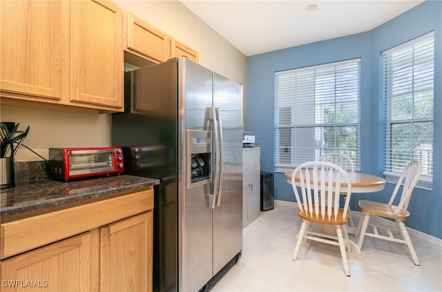 kitchen featuring stainless steel refrigerator with ice dispenser, light brown cabinets, and dark stone counters