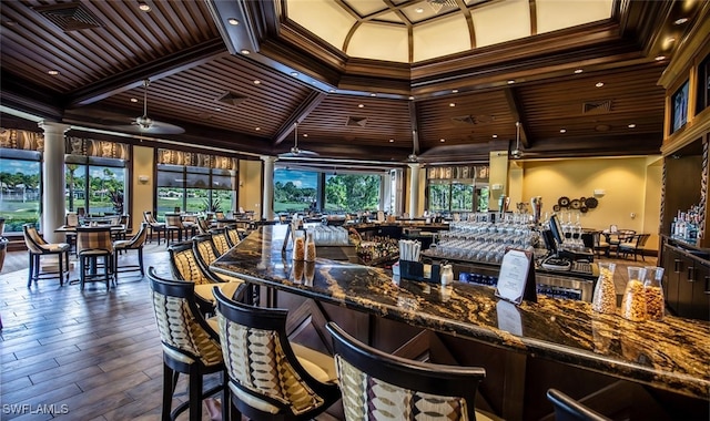 bar with ornamental molding, dark hardwood / wood-style floors, and dark stone counters