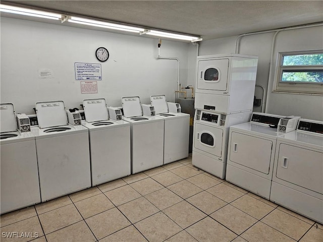 clothes washing area with stacked washing maching and dryer, washer and dryer, and light tile patterned floors