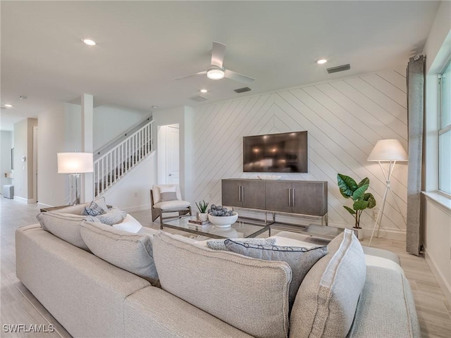 living room featuring wooden walls, light hardwood / wood-style flooring, and ceiling fan