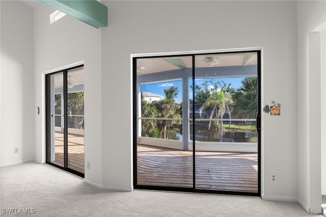 doorway with a wealth of natural light, a water view, and light colored carpet