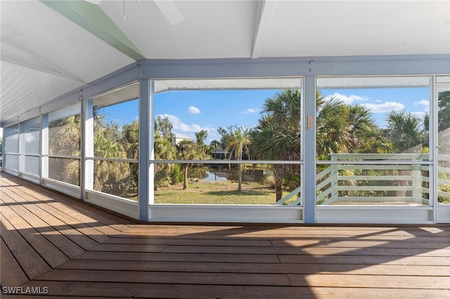 unfurnished sunroom featuring lofted ceiling with beams, a water view, and ceiling fan