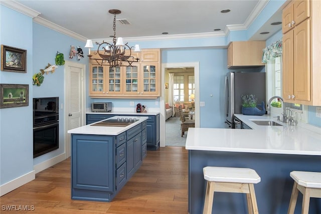 kitchen featuring a breakfast bar, sink, crown molding, kitchen peninsula, and stainless steel refrigerator