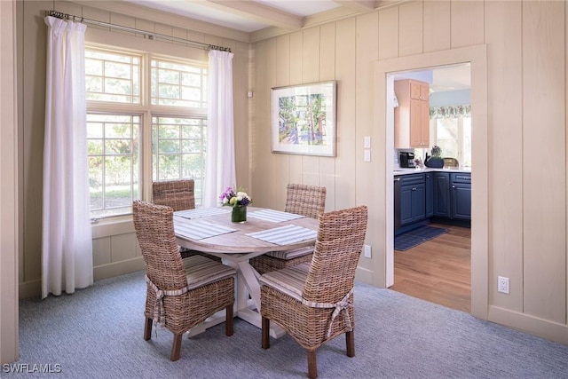 dining space featuring light carpet and beam ceiling