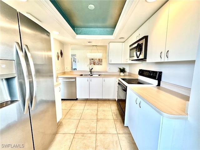 kitchen featuring light tile patterned floors, sink, appliances with stainless steel finishes, white cabinetry, and a raised ceiling