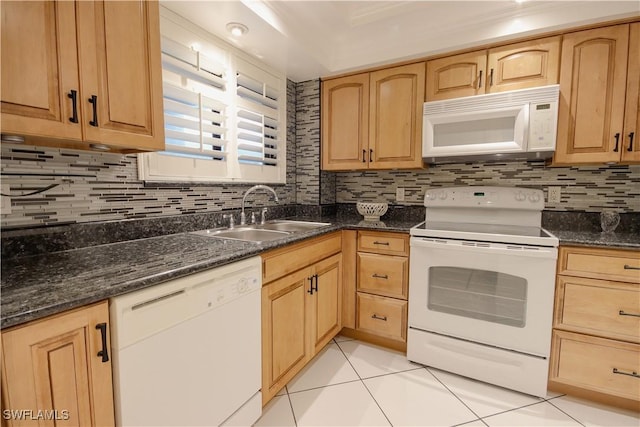 kitchen featuring white appliances, dark stone counters, tasteful backsplash, sink, and light tile patterned floors