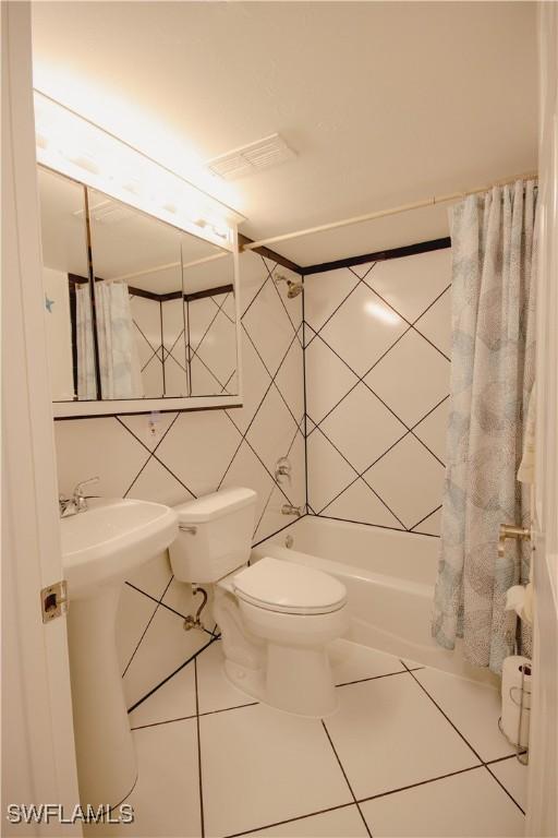 bathroom featuring tile walls, tile patterned floors, toilet, and shower / bath combination with curtain