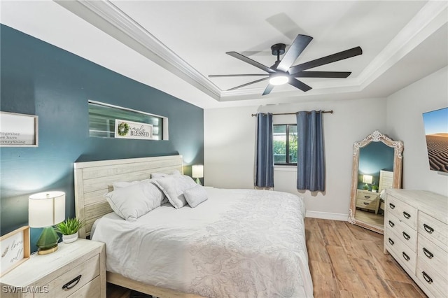 bedroom with ornamental molding, light hardwood / wood-style floors, a raised ceiling, and ceiling fan