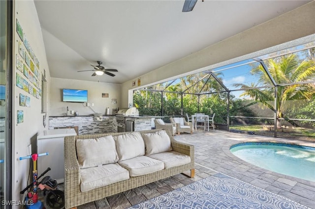 exterior space featuring a patio, an outdoor kitchen, an outdoor hangout area, and glass enclosure