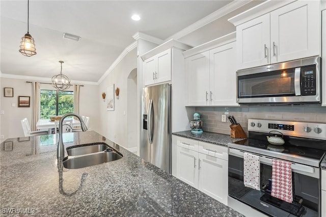 kitchen with sink, white cabinetry, hanging light fixtures, stainless steel appliances, and dark stone counters