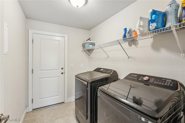 laundry room featuring light tile patterned floors, independent washer and dryer, and a textured ceiling