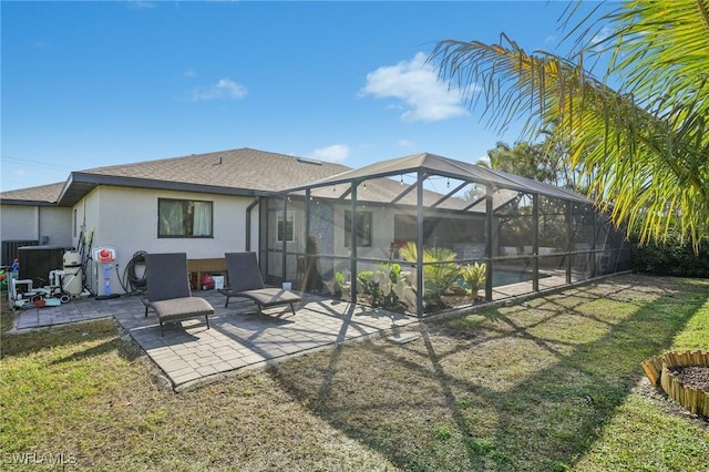 back of property with a pool, a patio, a yard, and glass enclosure