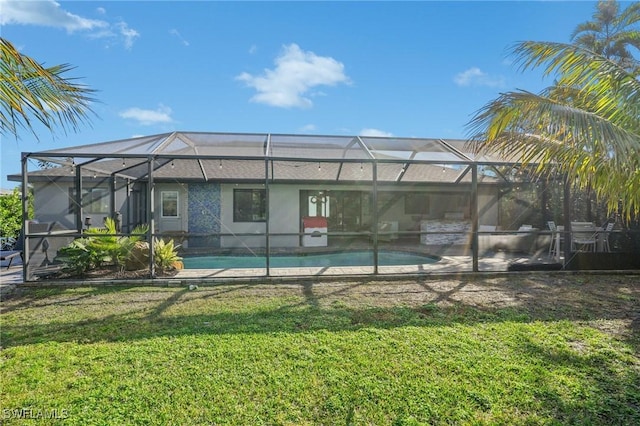 back of house featuring glass enclosure and a lawn