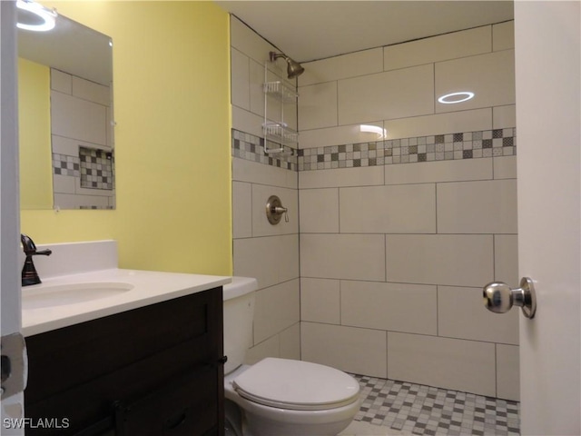 bathroom featuring vanity, toilet, and a tile shower