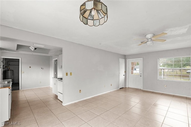 6135 Markland Ave, Fort Myers, FL 33916 - unfurnished living room featuring ceiling fan, baseboards, light tile patterned floors, and water heater