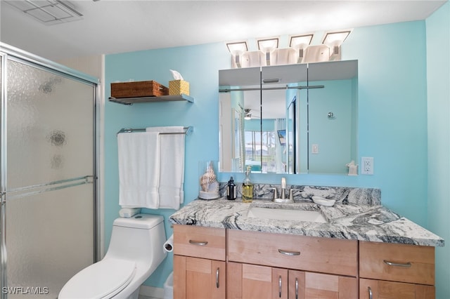 bathroom with vanity, a shower with door, and toilet