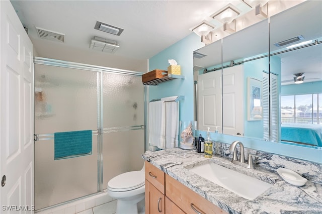 bathroom with ceiling fan, vanity, a shower with shower door, tile patterned floors, and toilet