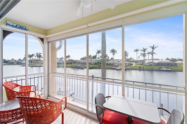 sunroom / solarium with a water view and ceiling fan