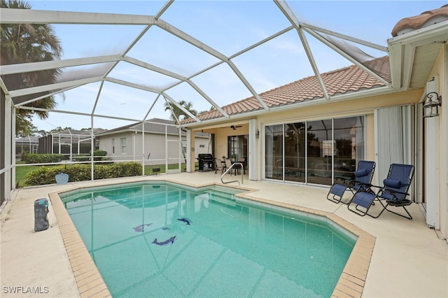 view of pool with ceiling fan, glass enclosure, grilling area, and a patio area