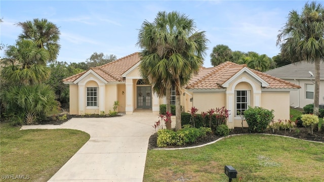 mediterranean / spanish house with a front yard and french doors