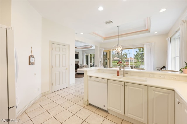 kitchen featuring pendant lighting, white appliances, sink, a raised ceiling, and light tile patterned floors