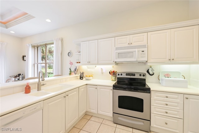 kitchen with white appliances, light tile patterned floors, sink, white cabinets, and backsplash