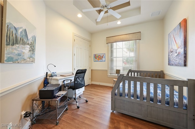 bedroom featuring ceiling fan, hardwood / wood-style flooring, and a tray ceiling