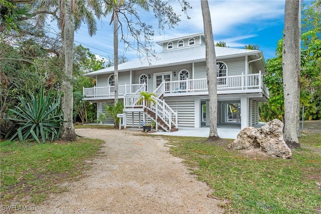 coastal inspired home featuring a front lawn, a carport, and covered porch