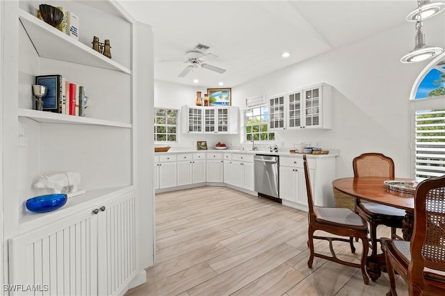 kitchen with sink, stainless steel dishwasher, pendant lighting, ceiling fan, and white cabinets