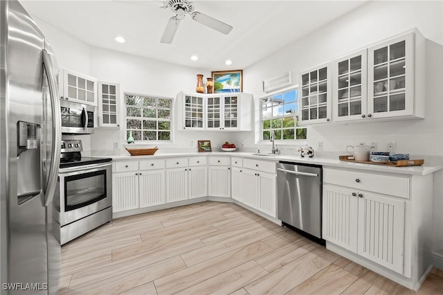 kitchen featuring sink, white cabinetry, light hardwood / wood-style flooring, ceiling fan, and stainless steel appliances