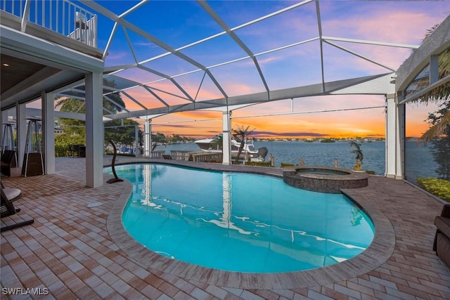 pool at dusk with a water view, an in ground hot tub, a patio area, and a lanai