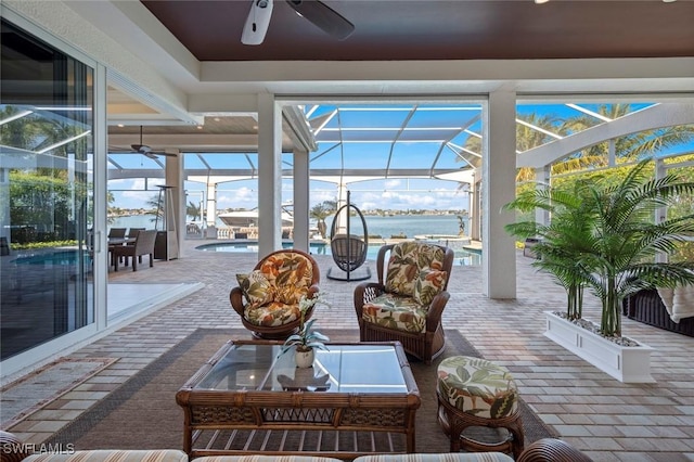 sunroom / solarium featuring ceiling fan and a water view