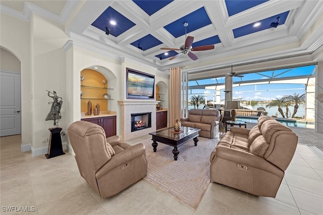 living room featuring ceiling fan, ornamental molding, coffered ceiling, and built in features