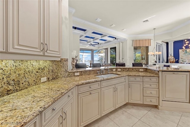 kitchen featuring coffered ceiling, light stone countertops, sink, and cream cabinetry