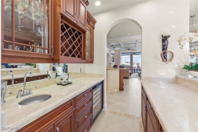 interior space featuring decorative light fixtures, sink, beverage cooler, light tile patterned floors, and light stone counters