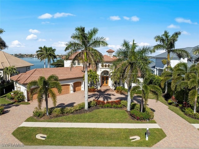 mediterranean / spanish house featuring a garage, a water view, and a front yard